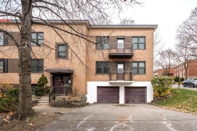 Duplex de brique beige à Westmount, deux portes de garage et entrée pavée, arbres sans feuilles